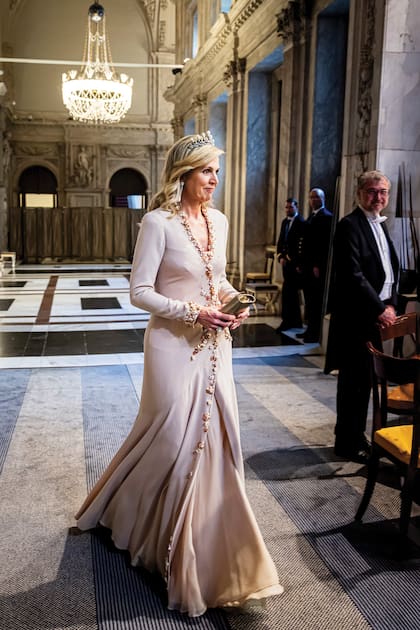 Con mangas largas, cuello cruzado y pedrería, el vestido que lució Máxima en la noche del lunes es un diseño creado por el holandés Jan Taminiau.